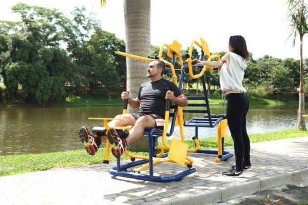 homem e mulher fazendo exercícios em equipamentos de academia ao ar livre